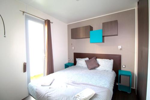 a bedroom with a bed with white sheets and a window at Lodges camp in Setúbal