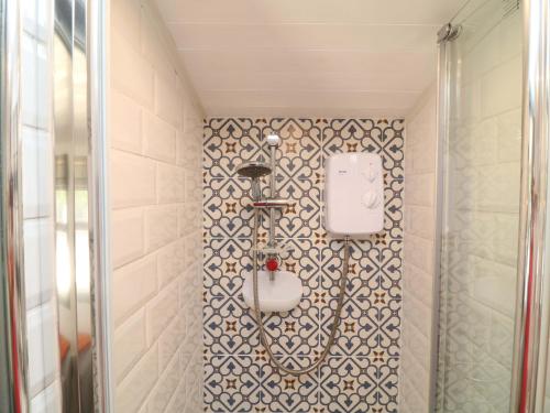 a shower in a bathroom with a tile wall at Lake View Shepherds Hut in Lincoln