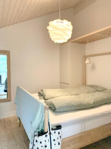 a bedroom with a bed and a pendant light at Modern And Stylish Summer Cabin in Vejby