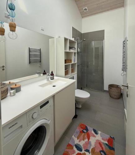 a white bathroom with a washing machine in it at Modern And Stylish Summer Cabin in Vejby