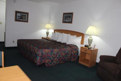 a hotel room with a bed and a chair at Americas Best Value Inn Grand Forks in Grand Forks