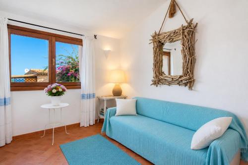 a living room with a blue couch and a window at Sea View Within Walking Distance of the Beach in Baja Sardinia