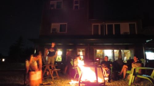 a group of people sitting around a fire at night at Le Gîte Ambrelane in Thetford Mines