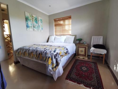 a bedroom with a bed and a chair and a window at Somerset Grace Cottage in Somerset West