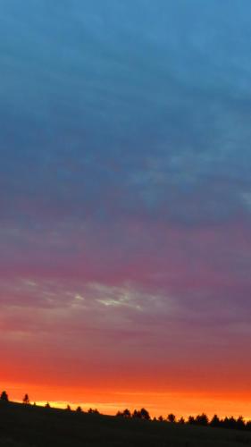 a colorful sky at sunset with a field and trees at Le Gîte Ambrelane in Thetford Mines
