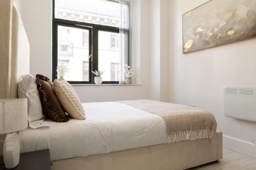 a white bedroom with a bed and a window at Bradford Chic City-Centre Apartment in Bradford