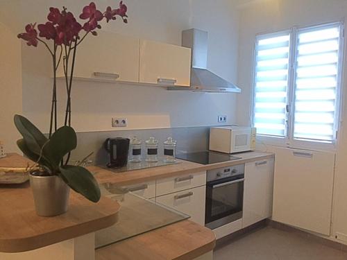 - une cuisine avec un vase orné de fleurs violettes dans l'établissement Le Palais Martine, à Nice