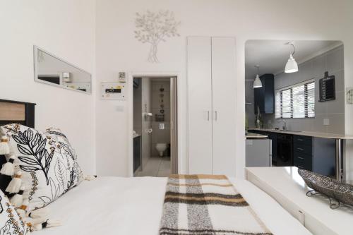a white room with a bed and a kitchen at La Mer 14 in Ballito