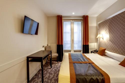 パリにあるホテル ダミアンのベッドとデスクが備わるホテルルームです。