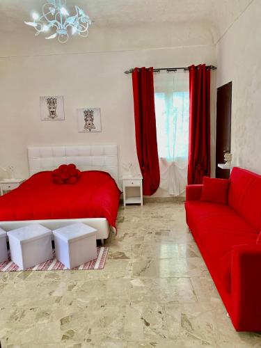 a bedroom with a red bed and a couch at Sicilia Benessere in Montedoro