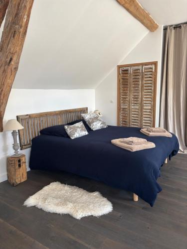 a bedroom with a bed with a blue blanket and pillows at La Vieille Demeure in Barbizon