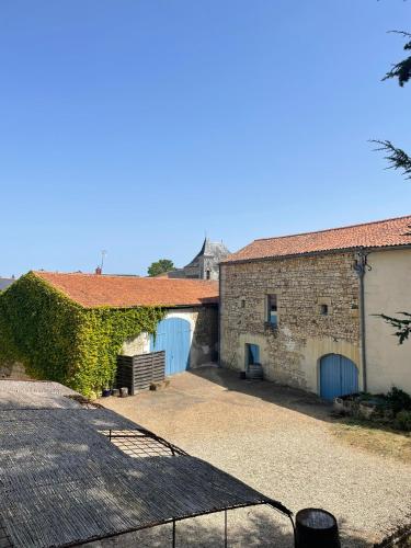 a building with two blue doors and a hedge at Sirona - domaine viticole et chambres d'hôtes in Le Puy-Notre-Dame