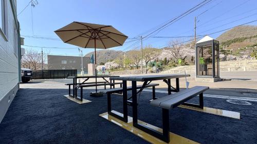 a group of picnic tables with an umbrella at Ts House Hakodate Park Front in Hakodate