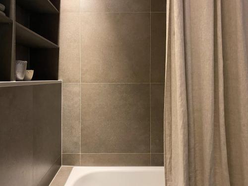 a bathroom with a shower curtain and a bath tub at Haus am Felsen, Ferien in Vorarlberger Architektur in Bregenz
