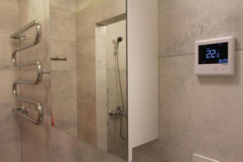 a bathroom with a shower with a clock on the wall at Central Boulevard Apartment in Šiauliai