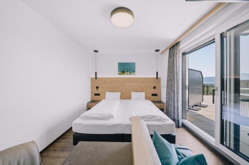 a bedroom with a bed and a balcony at Hotel Alpenblick Attersee Superior in Attersee am Attersee