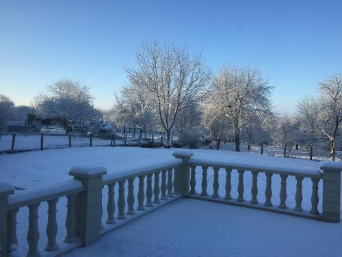 a fence covered in snow with trees in the background at Bienvenue A La Campagne in Villers-sur-Port