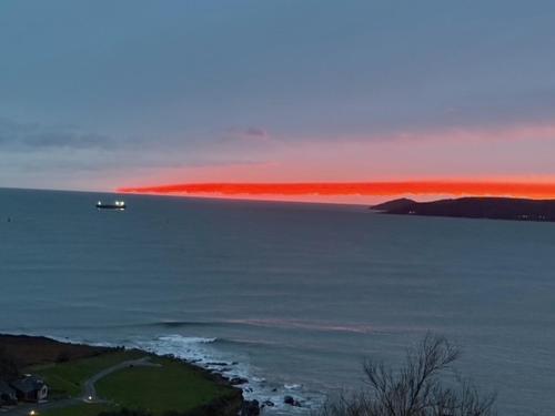 a boat in the ocean with a red horizon at Crownhill Bay House in Plymouth