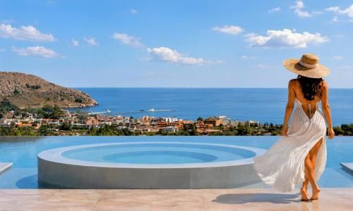 a woman in a white dress standing next to a swimming pool at Mistral Suite Heated Pool in Georgioupoli