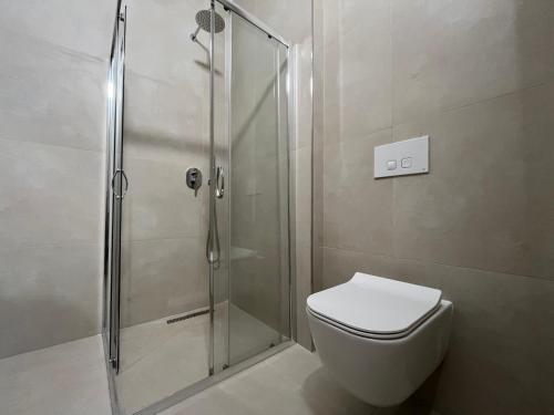 a bathroom with a toilet and a glass shower at Palm Apartments Radhime in Vlorë
