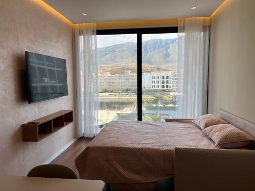a bedroom with a bed and a large window at Palm Apartments Radhime in Vlorë