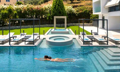 a woman laying in a swimming pool in a hotel at Mistral Suite Heated Pool in Georgioupoli