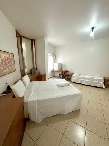a bedroom with two beds and a table and chairs at Hotel Minas Palace in Passos