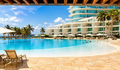 a pool with chairs and umbrellas in front of a hotel at Aria Ocean in Nuevo Vallarta