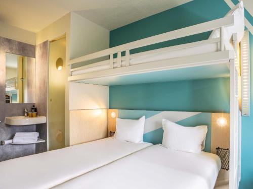 a bedroom with a bunk bed with white pillows at ibis budget Haguenau Strasbourg Nord in Haguenau