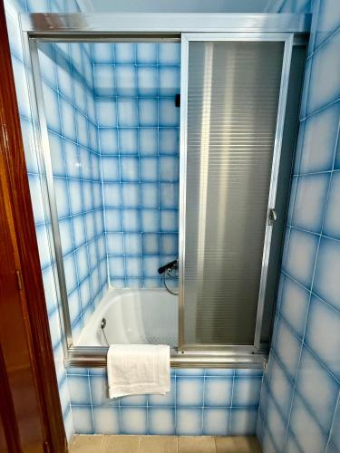 a blue tiled bathroom with a tub and a mirror at Casa Noël in Puertollano