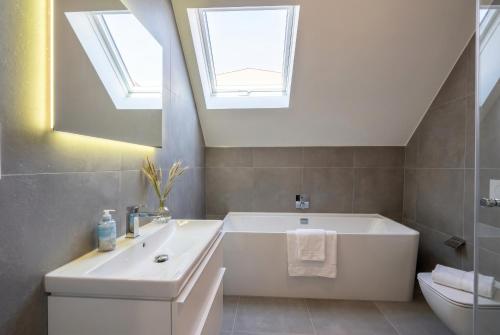 ein Badezimmer mit einer weißen Badewanne und einem Waschbecken in der Unterkunft 2 Schlafzimmer, Offene Küche, Balkon und Terrasse - moderne 90qm in ruhiger, zentraler Lage - nur 500m bis zum Strand in Warnemünde