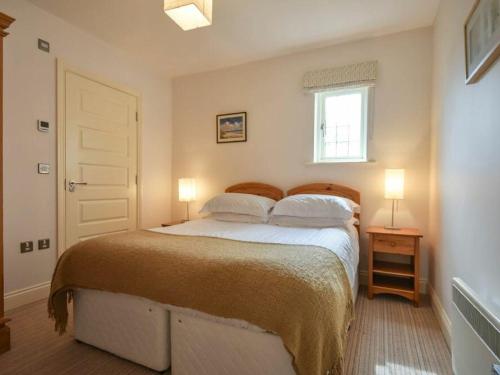 a bedroom with a bed with two lamps and a window at Northrawe in Bamburgh