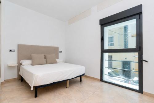 a bed in a room with a window at Casa 2 Hab con Terraza & Barbacoa en Ubicación Céntrica in Gandía