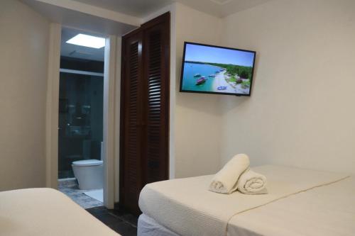 a room with two beds and a television on the wall at Peixe Crew Centro in Búzios