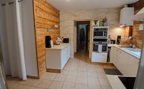 a kitchen with white appliances and a wooden wall at Maison de ville in Pont-Saint-Esprit