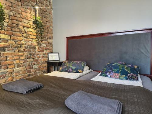 two beds in a room with a brick wall at Flores Apartament in Katowice