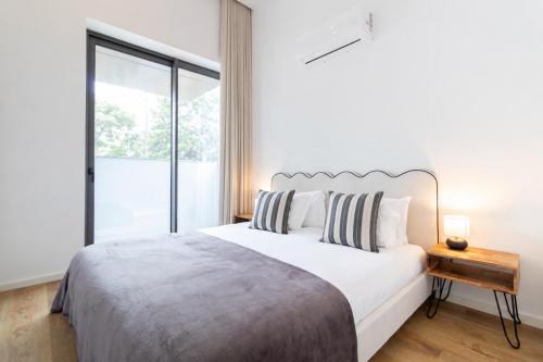 a white bedroom with a large bed and a window at ASTRO Emanuelle E by LovelyStay in Leça da Palmeira