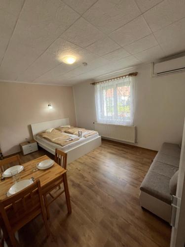 a room with a bed and a table and a couch at Liliom Vendégház in Bakonybél