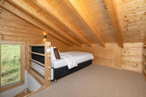 a bedroom in a log cabin with a bed and a window at Chalet Amerhone - Luxury chalet With Jacuzzi in Riddes