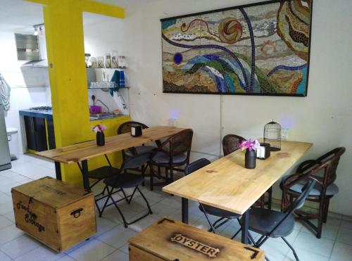 two tables and chairs in a kitchen with a painting on the wall at Oyster Hostel in Veracruz