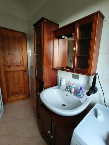 a bathroom with a white sink and wooden cabinets at Villa Carol in Polinago