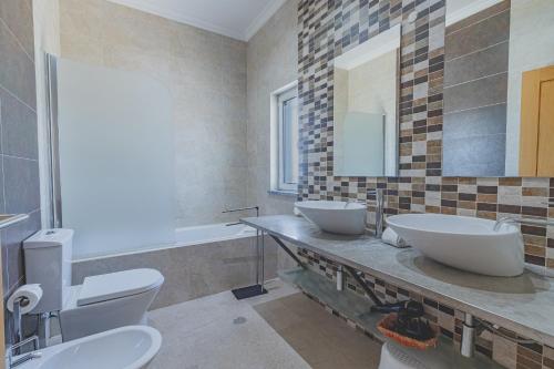 a bathroom with two sinks and a toilet and a tub at Villa Belchior by Algarve Holidays in Faro