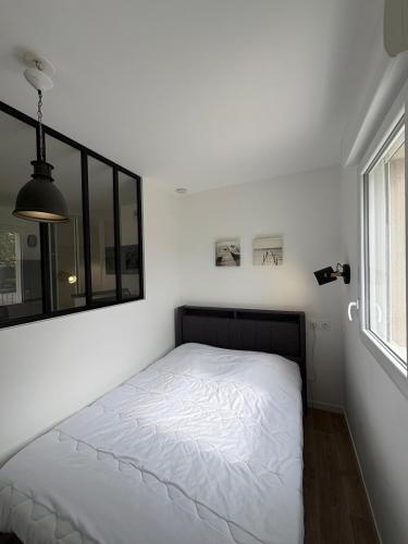 a white bed in a room with a window at Studio with garden in Dinard