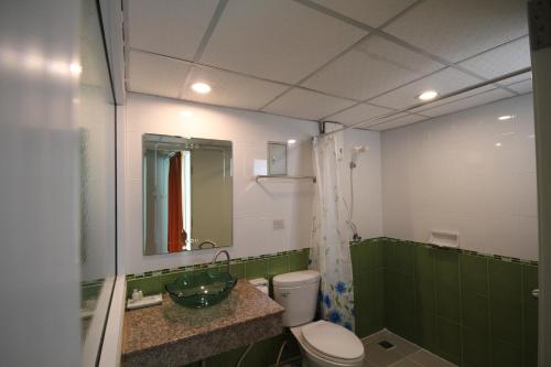 a green and white bathroom with a toilet and a sink at J.Residence in Samut Prakan