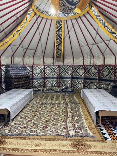 a room with two beds and a rug in a yurt at Murat Lyazzat Hotel in Kurmenty