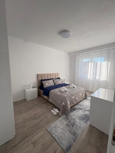 a white bedroom with a bed and a window at ARMAS Stay in Kamëz
