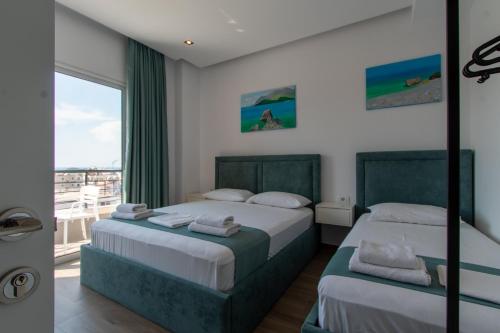 a bedroom with two beds and a balcony at D&D HOTEL Ksamil in Ksamil