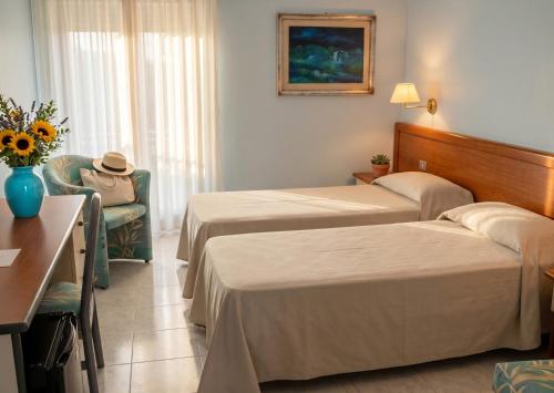 a hotel room with two beds and a chair at Eden Torre Canne in Torre Canne