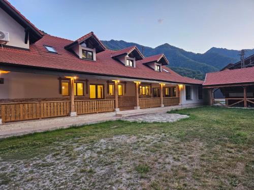 a house with a red roof and a yard at Cuib de Munte in Brezoi