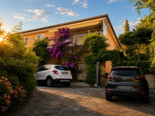two cars parked in front of a house with flowers at Apartments Furlan in Portorož